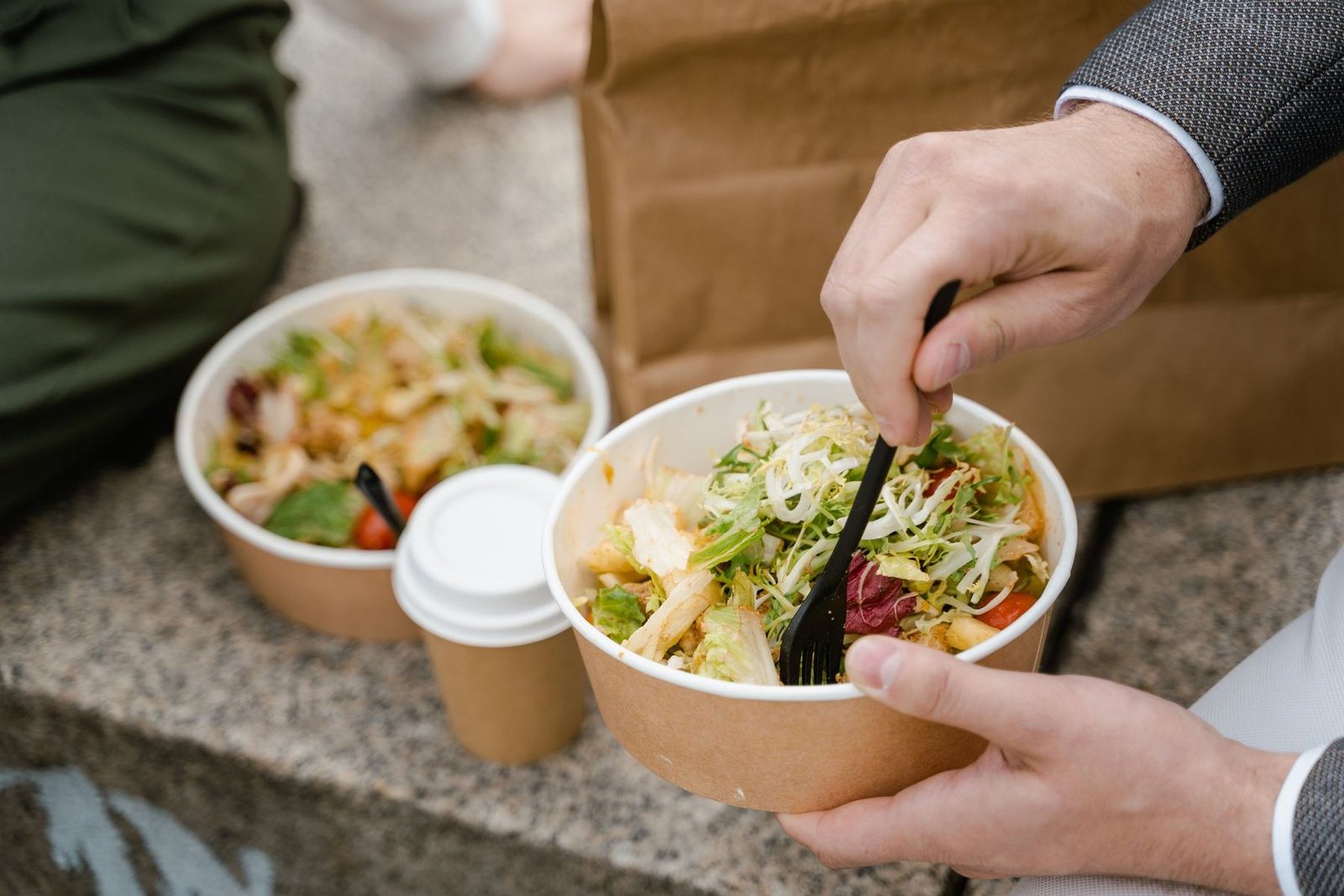 Dos personas comiendo ensaladas en bowls compostables en un descanso
