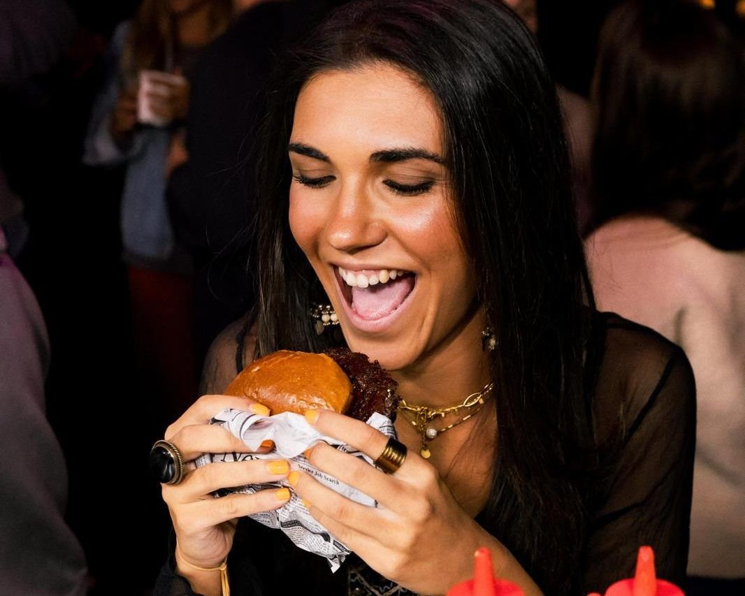 Clienta disfrutando de una hamburguesa de Q Street Food en un evento