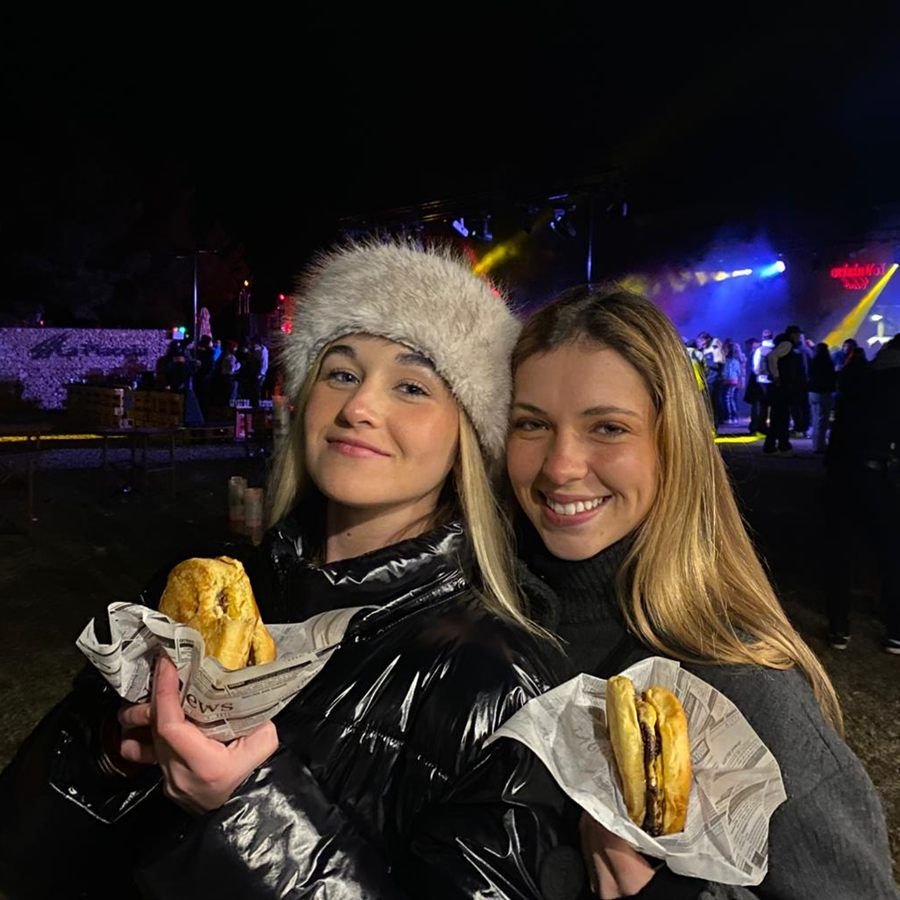 Dos clientas con hamburguesas de Q Street Food en un festival nocturno