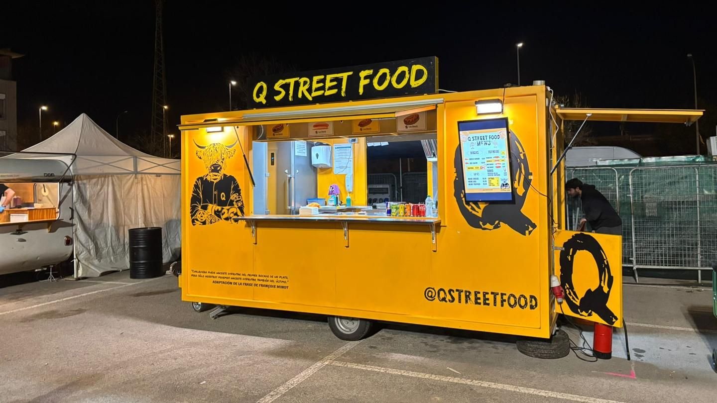 Food truck amarillo de Q Street Food preparado para un evento nocturno